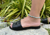 Zoomed-in photo of a model wearing irregular beads stackable beach anklet from Hill to Street with black open-toe shoes